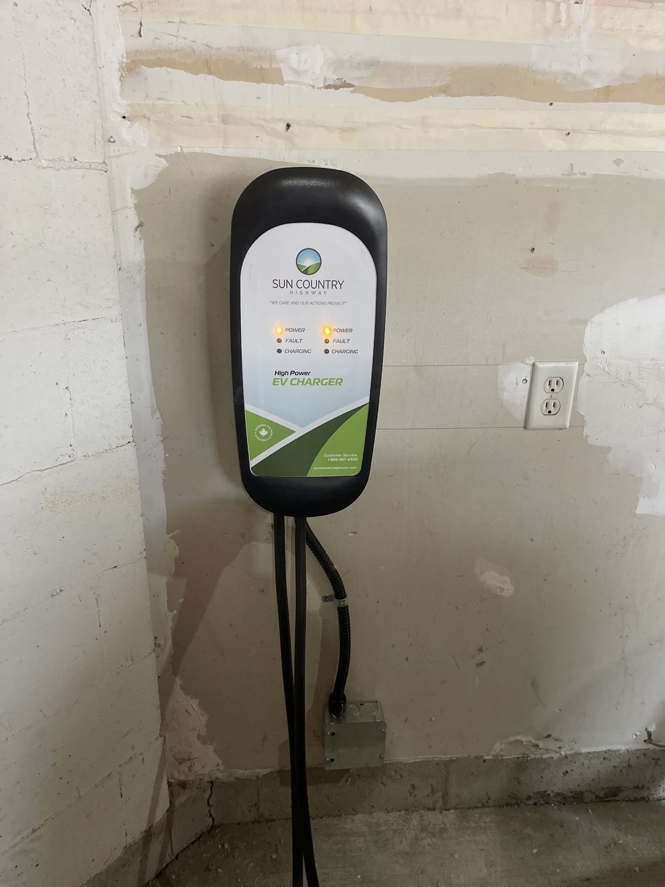 A wall-mounted EV charger beside a new outlet