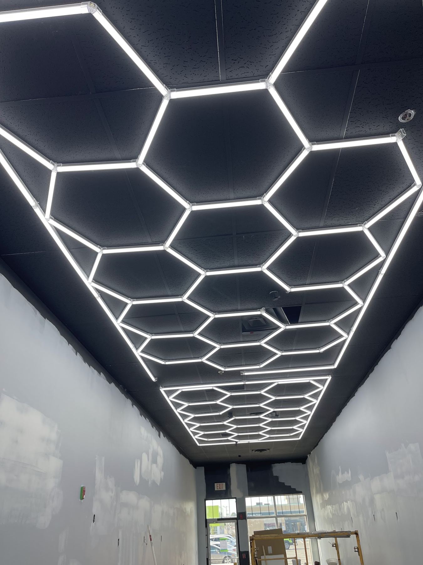 A ceiling of connected hexagon LED lights in a long garage