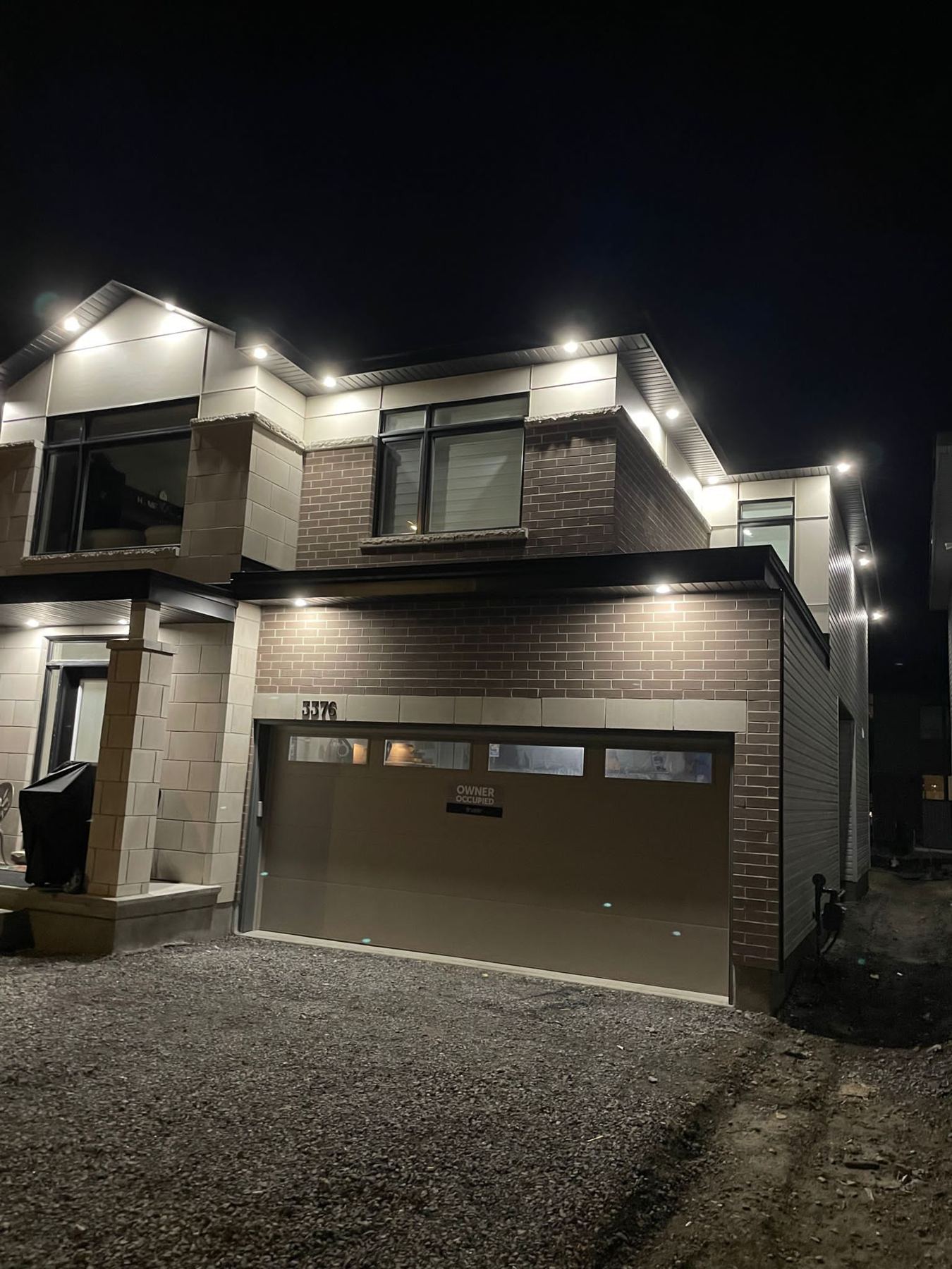 A new two-storey house at night lit by pot lights in the soffits