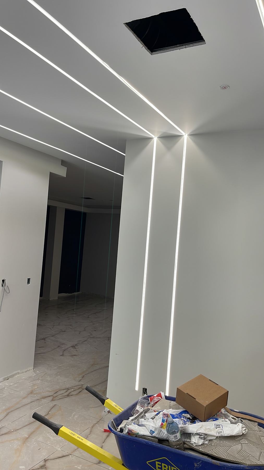 Linear light slots running across a ceiling and down a wall corner